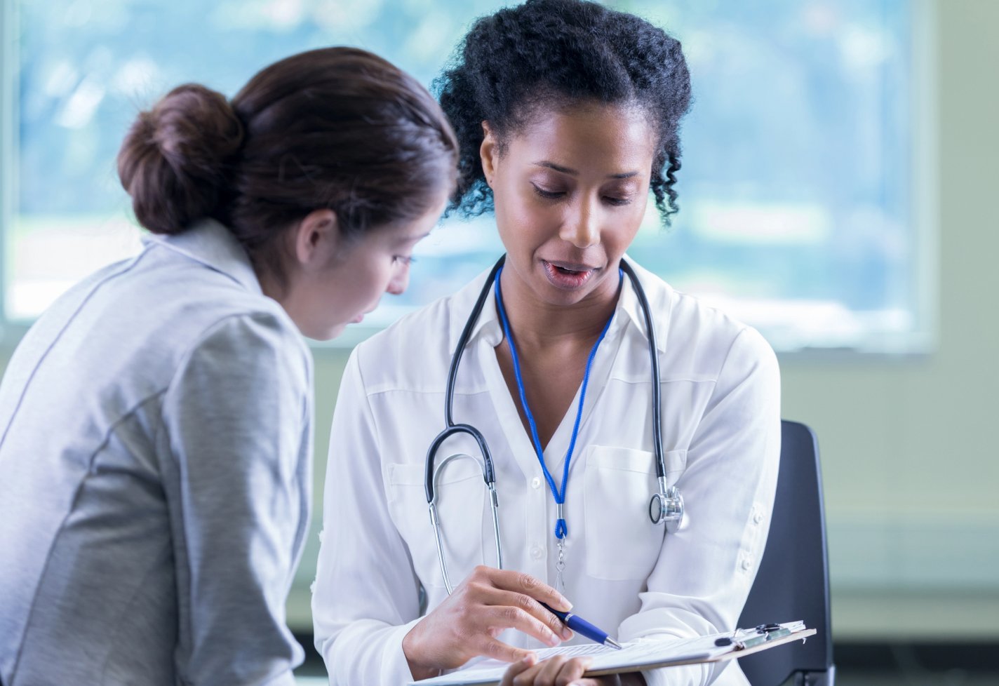 Female doctor speaking with a female patient in a medical office Female doctor speaking with a female patient in a medical office